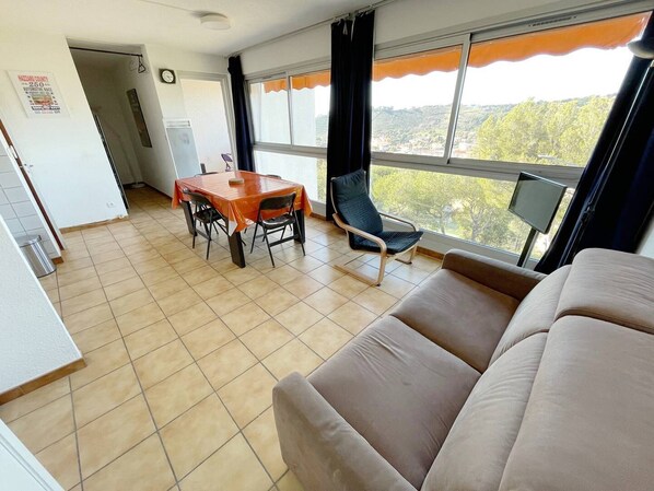 A room with a dining table, chairs, a sofa, and a TV.
