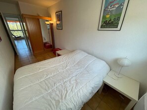 A bedroom with a large bed, a bedside table, and a poster on the wall.
