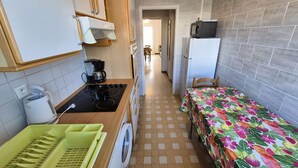 Eine kompakte Küche mit Waschmaschine, Mikrowelle und Kühlschrank.