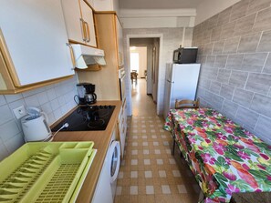 Een kleine keuken met een wasmachine, een magnetron en een koelkast.