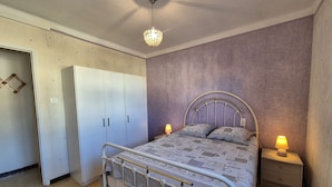 Ein Schlafzimmer mit Bett, Nachttischen, einem Kleiderschrank und einer Deckenleuchte.