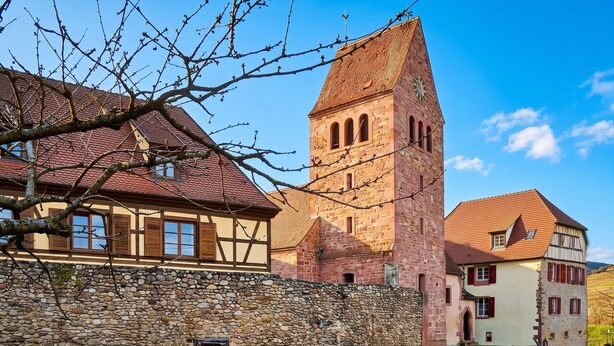 A traditional European building with a stone wall, a tower with arched windows, and a two-story house with a red-tiled roof. - Homerez - Apartment in Kientzheim (Kientzheim)