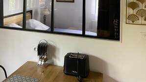 A room with a large window, a black pendant light, a toaster, and a knife holder on a table.