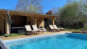 A wooden cabin with a pool and lounge chairs.