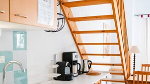 A kitchen with a wooden ladder, a coffee maker, and a kettle on the counter.