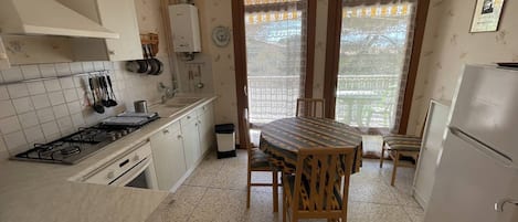 Een koelkast, een oven, kookgerei, borden en bestek