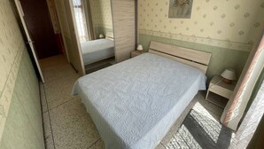 Une chambre à coucher avec un lit, un miroir, un ventilateur de plafond et un tableau accroché au mur.