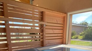 Un jacuzzi con cerramiento de vidrio, escalones de madera y vistas al exterior.