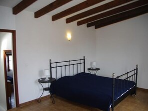 A bedroom with a single bed, two bedside tables, and a wall-mounted light fixture.
