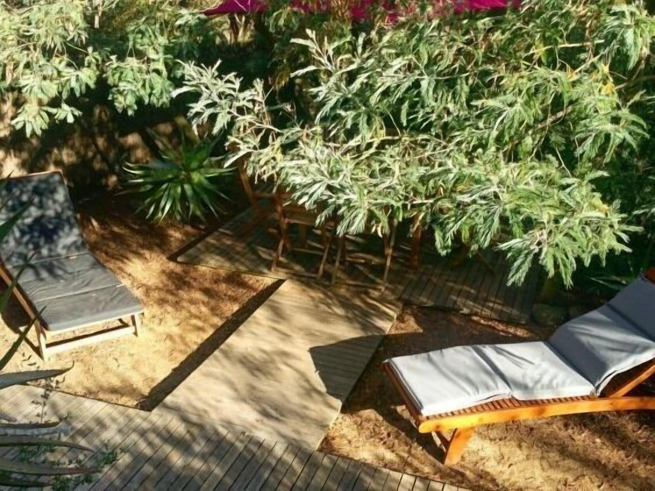 Ein Gartenbereich mit zwei Liegestühlen und einem Holztisch.