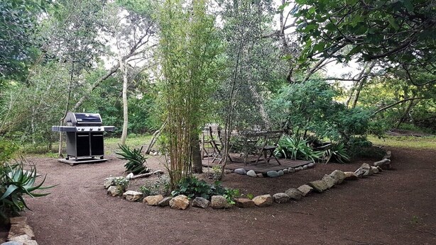A barbecue grill, a wooden deck, and a garden with rocks and plants. - Studio & large garden 200m Calvi beach (Calvi)