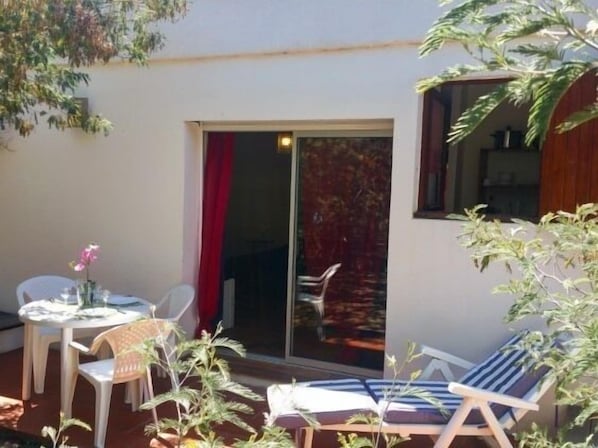 Un área de estar al aire libre con una mesa, sillas y una tumbona.