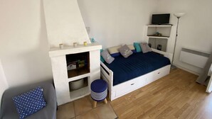 Une chambre à coucher avec un lit, une petite étagère, un téléviseur et un radiateur.