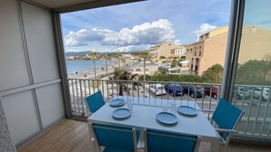 Un balcon avec une table et des chaises, donnant sur une plage et des immeubles.