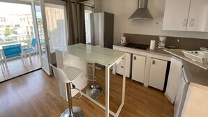 Une cuisine moderne dotée d’un îlot central, de tabourets de bar, d’un four encastré et d’une grande fenêtre avec des rideaux.