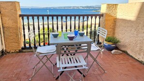 Un piccolo patio esterno con tavolo e due sedie, una pianta in vaso e vista sul mare.