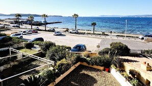 Una strada costiera con auto parcheggiate, un attraversamento pedonale e vista sul mare.