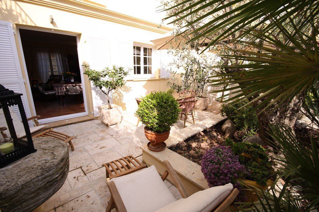 An outdoor patio with stone flooring, a wooden chair, a potted plant, and a small table.