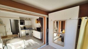 Een kleine hotelkamer met een bed, een kitchenette, een eethoek en een badkamer.