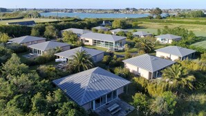 A residential area with multiple houses, each featuring a distinct architectural style, surrounded by lush greenery and a body of water in the background.
