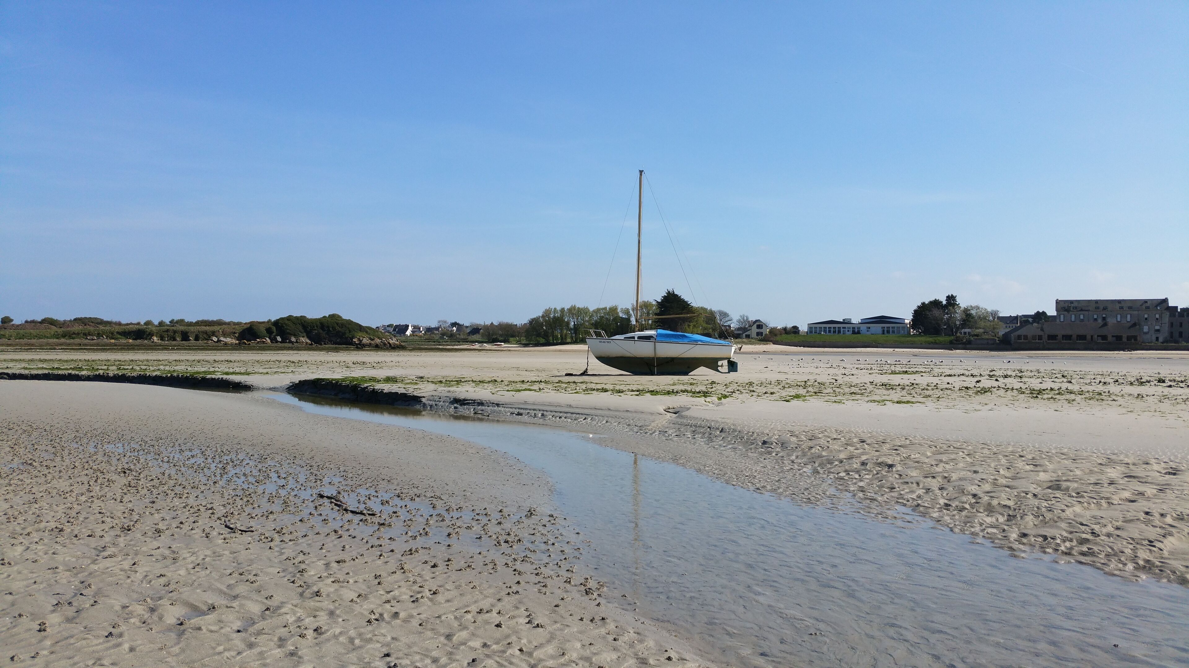 A boat on a sandy beach with a clear sky.