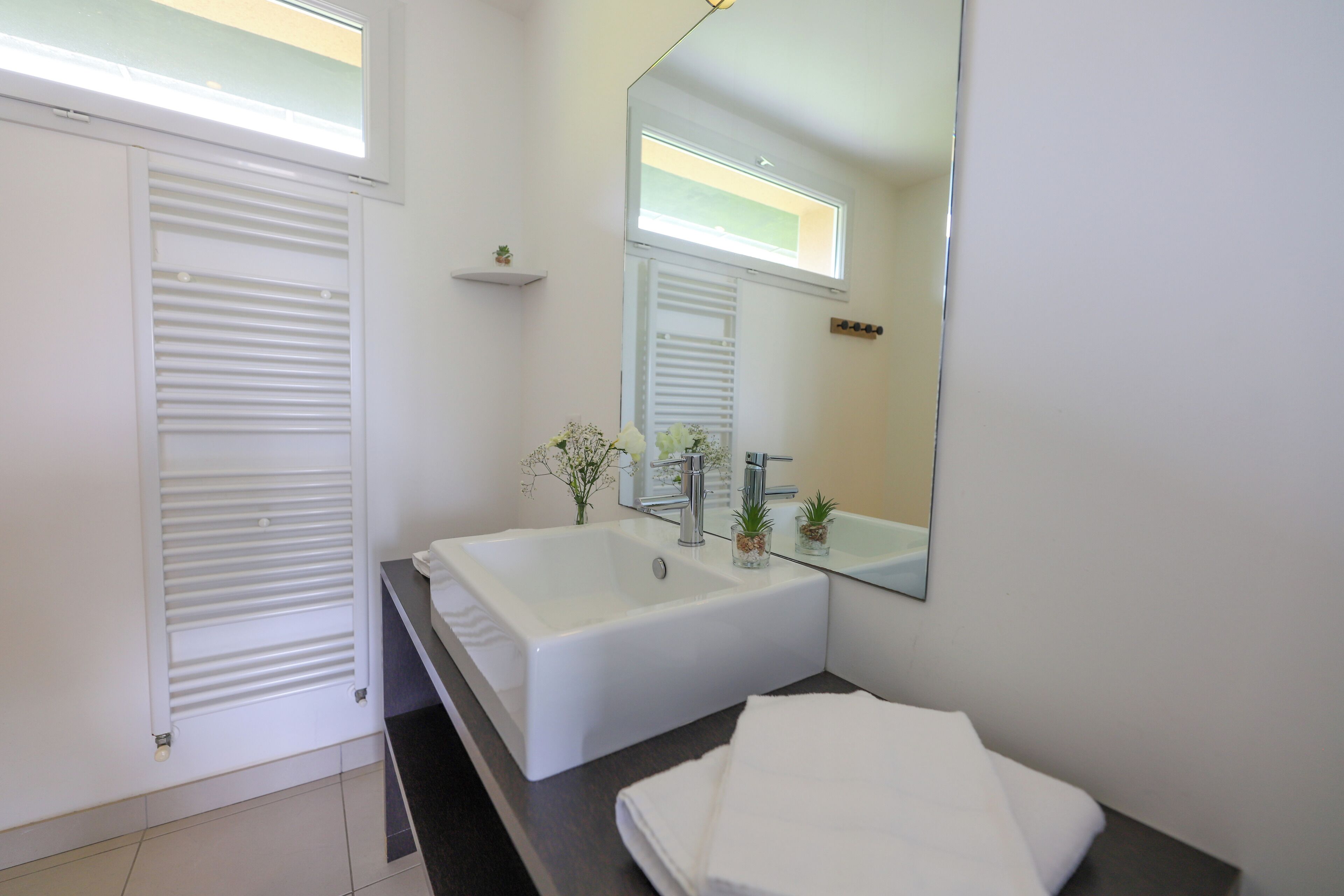 A modern bathroom with a large bathtub, a sink, and a mirror.