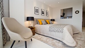 Une chambre moderne avec un lit, deux tables de chevet, une chaise et un miroir.