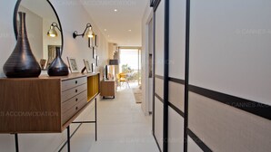 Un couloir d’hôtel moderne avec une commode en bois, deux lampes fixées au mur et un grand miroir.