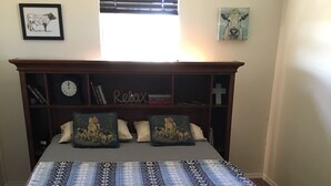 Un dormitorio con una cama, cabecera de madera, un reloj y una ventana con persianas.