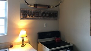Una cocina con un cartel que dice 'WELCOME', una lámpara, una tetera y un lavabo.