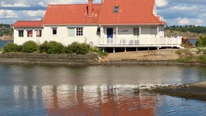 Una casa blanca con techo rojo junto a un lago.
