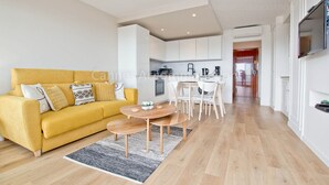 A modern living room with a yellow sofa, a small wooden table, and a kitchen in the background. - Tulette-2040-Convenient apartment with view (Cannes)