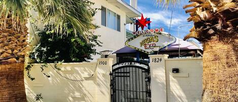 L’entrée d’un hôtel, avec une enseigne sur laquelle on peut lire « Bienvenue au paradis », et une tour en arrière-plan.