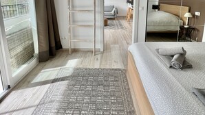 Una camera da letto moderna con un letto grande, una scala in legno, un tappeto decorato e vista attraverso un'ampia finestra.