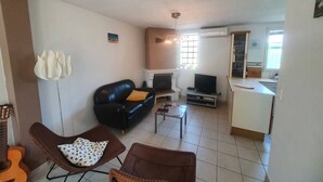 A living room with a black leather sofa, a brown armchair, a small coffee table, a guitar, and a fireplace. - Beachfront, Comfortable, AIR CONDITIONER (ST MANDRIER SUR MER)