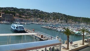 A marina with boats docked, a covered walkway, and a hillside in the background. - Beachfront, Comfortable, AIR CONDITIONER (ST MANDRIER SUR MER)