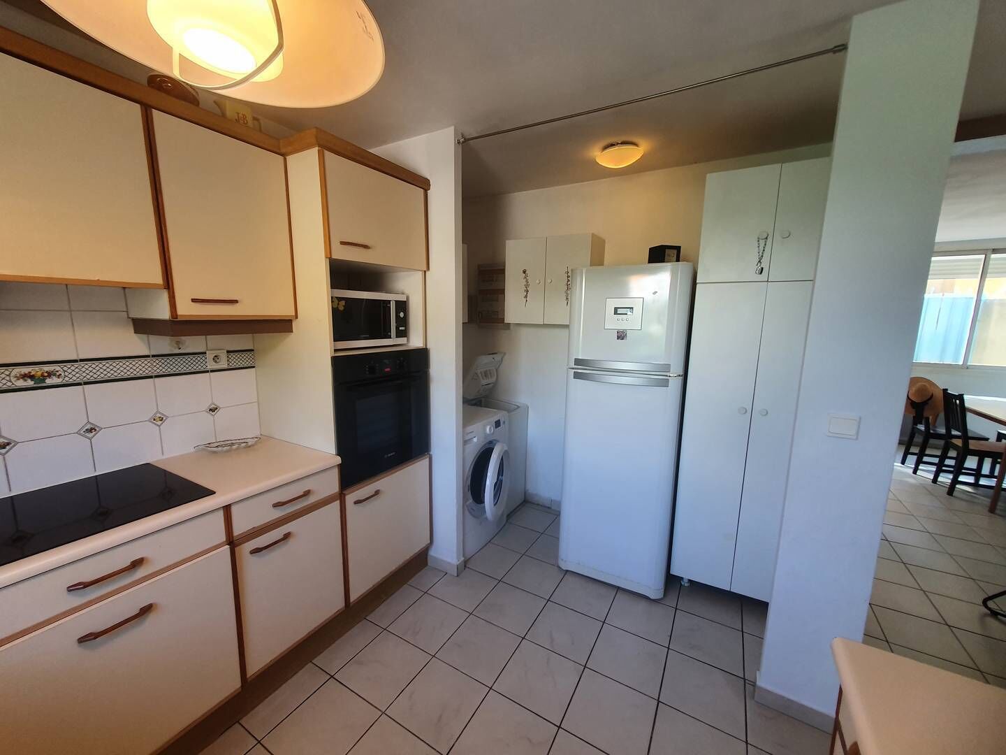 Een praktische keuken met een magnetron, oven, wasmachine en koelkast.
