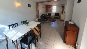 A dining area with a table and chairs, a living room with a sofa and TV, and a kitchen area with cabinets. - Beachfront, Comfortable, AIR CONDITIONER (ST MANDRIER SUR MER)