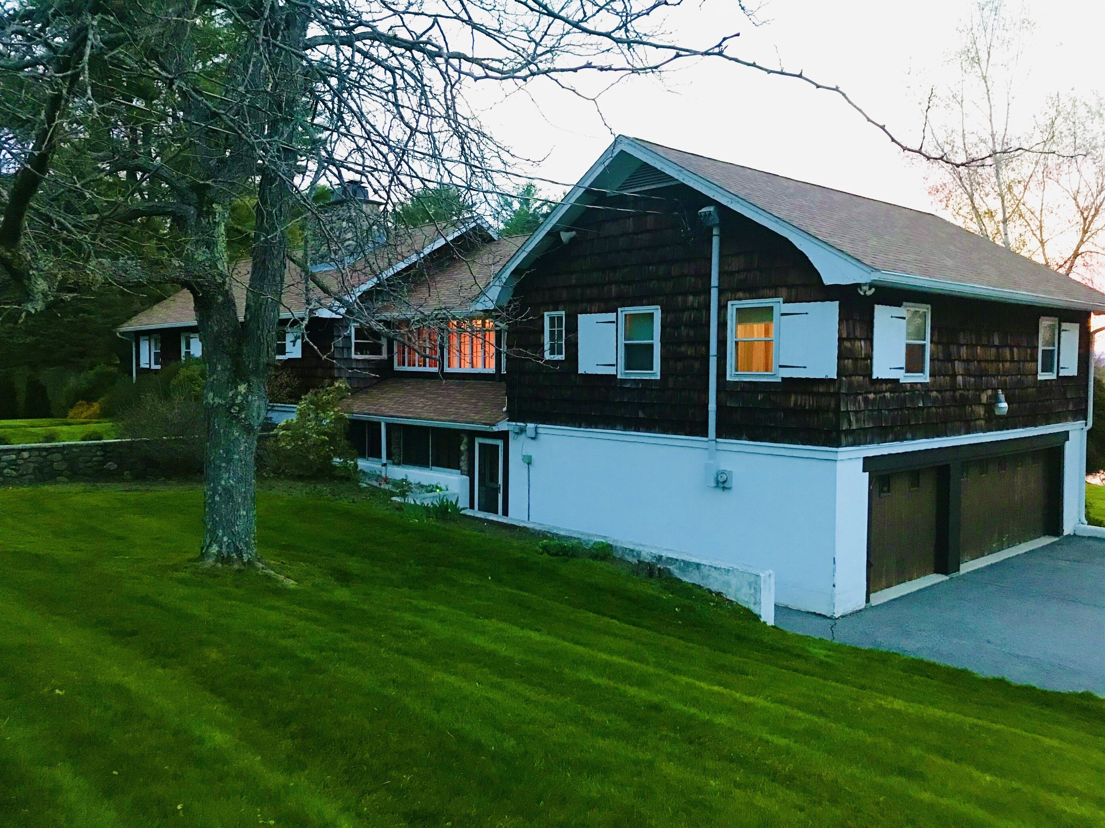 Une maison à deux étages avec un garage, une véranda et une pelouse bien entretenue.