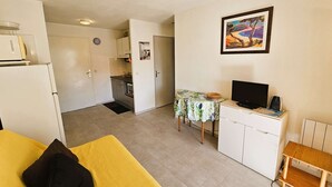 Kompakti hotellihuone, jossa on sänky, työpöytä ja televisio, pieni keittonurkkaus sekä ruokailutila.