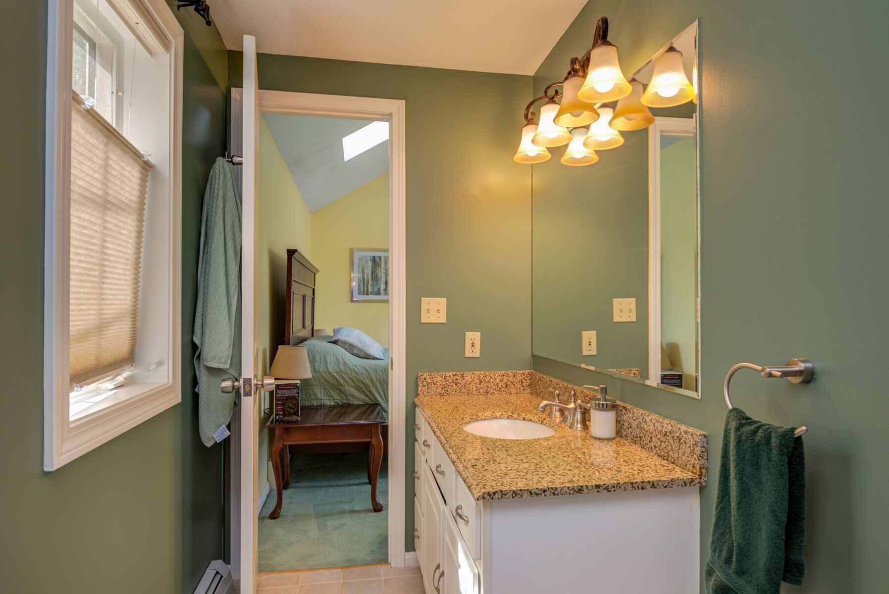 A bathroom with a granite countertop sink, a mirror, and a shower.