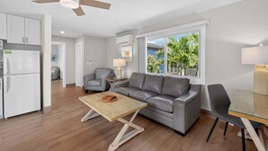 Un salon moderne comprenant un canapé, une table basse, une table à manger et un ventilateur de plafond.