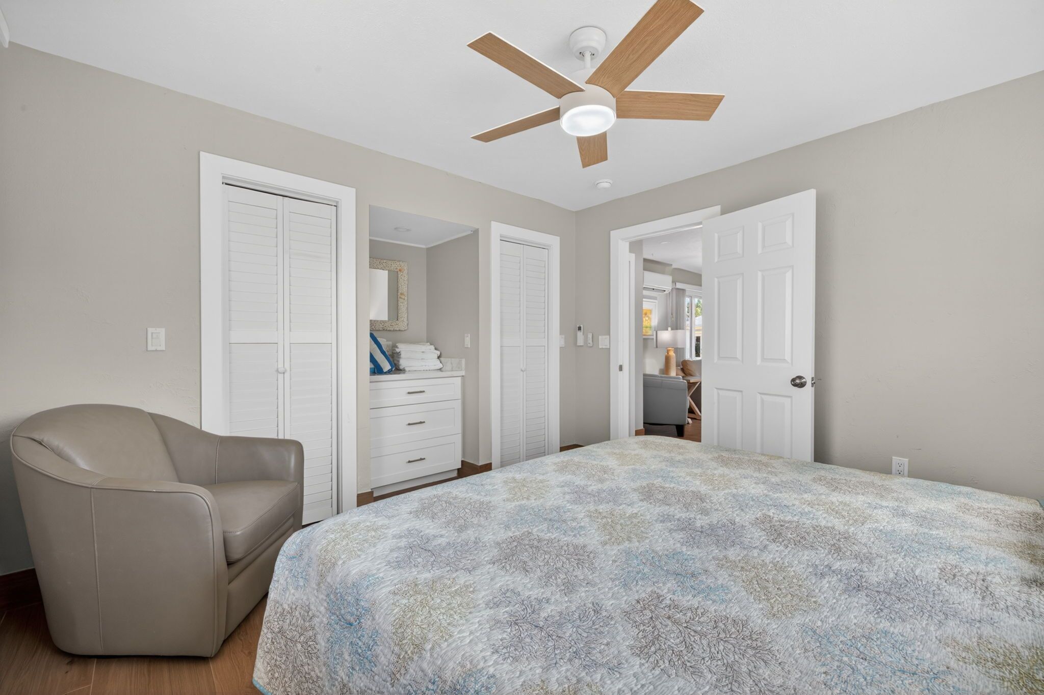 Ein Schlafzimmer mit Bett, Deckenventilator, Stuhl und Kleiderschrank.