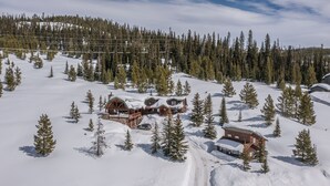Un albergue con varias cabañas rodeado de terreno nevado y pinos.
