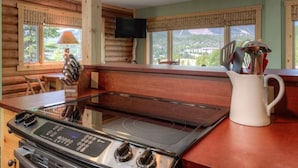Una cocina con estufa, televisor y vistas al exterior.