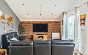 Una sala de estar con pared de ladrillo, sofá de cuero, televisión de pantalla plana y un mural de mapa mundial.