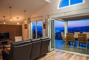 A modern living room with a leather sofa, a flat-screen TV, and a balcony with wooden chairs. - PENTHOUSE with SPECTACULAR SEA VIEW (Hvar)