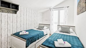 A double room with two beds, each with a teal bedspread and white pillows, a wooden headboard, and a small shelf above the beds. - PENTHOUSE with SPECTACULAR SEA VIEW (Hvar)