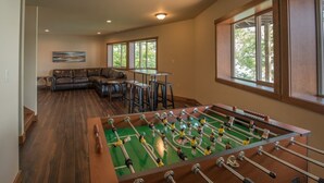 A spacious living area with a foosball table, a leather couch, and a dining table.