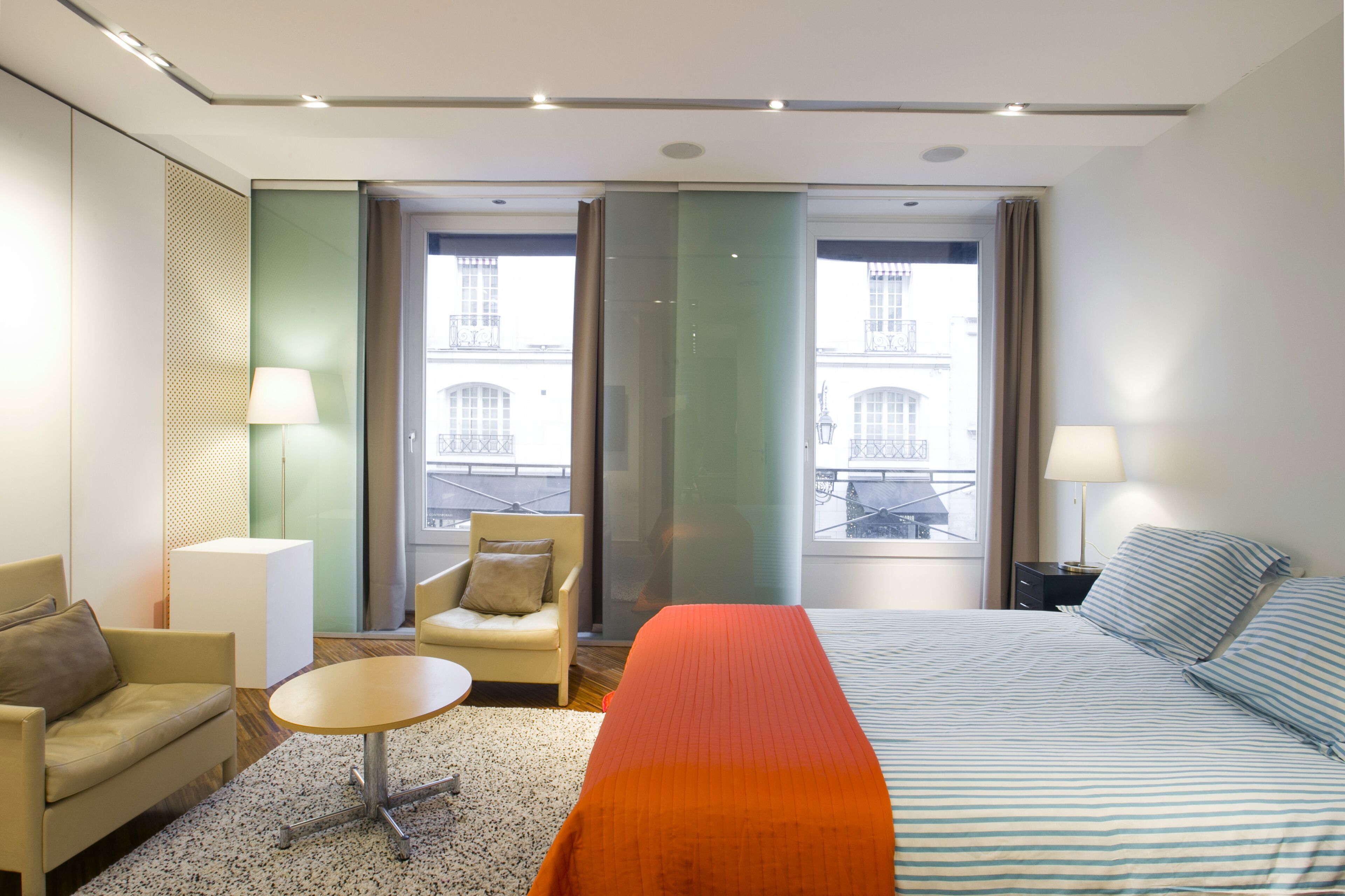 Una camera d'albergo con un letto, un divano, una poltrona, un tavolino e una lampada.
